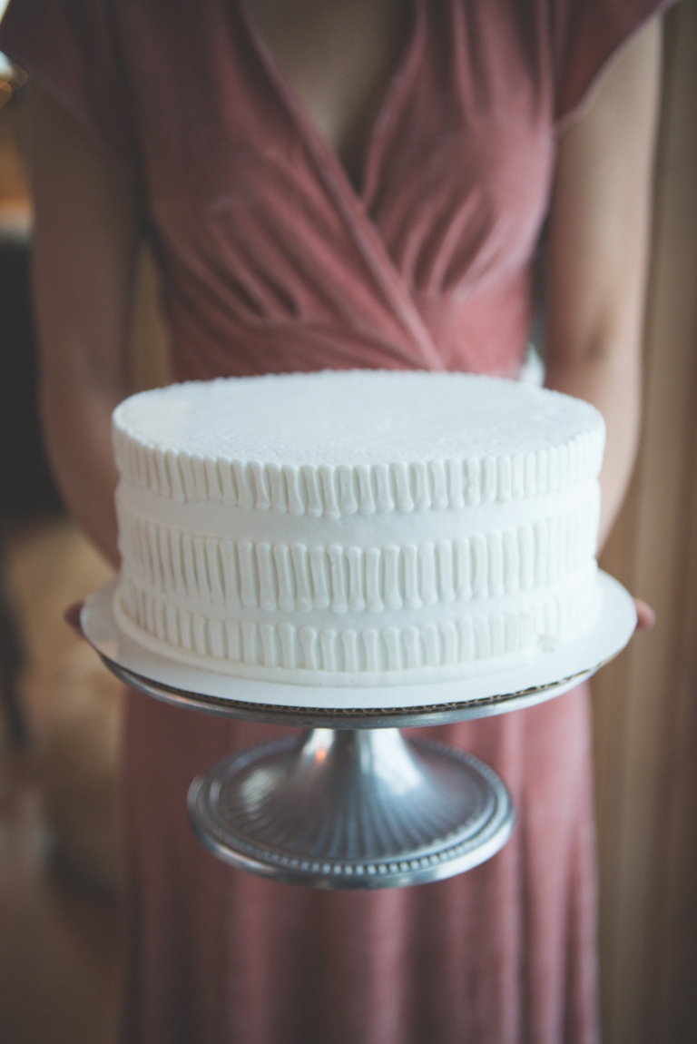 bridesmaid holding simple white wedding cake